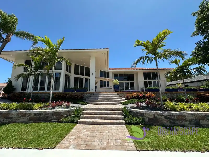 After: A waterfront home in Fort Lauderdale: a worn lawn and old steps became stone walls, paver steps, palms and colorful planting
