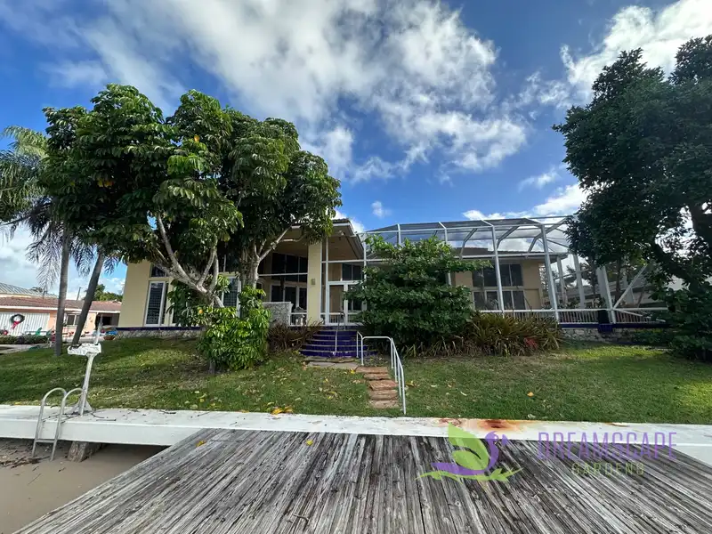 Before: A waterfront home in Fort Lauderdale: a worn lawn and old steps became stone walls, paver steps, palms and colorful planting